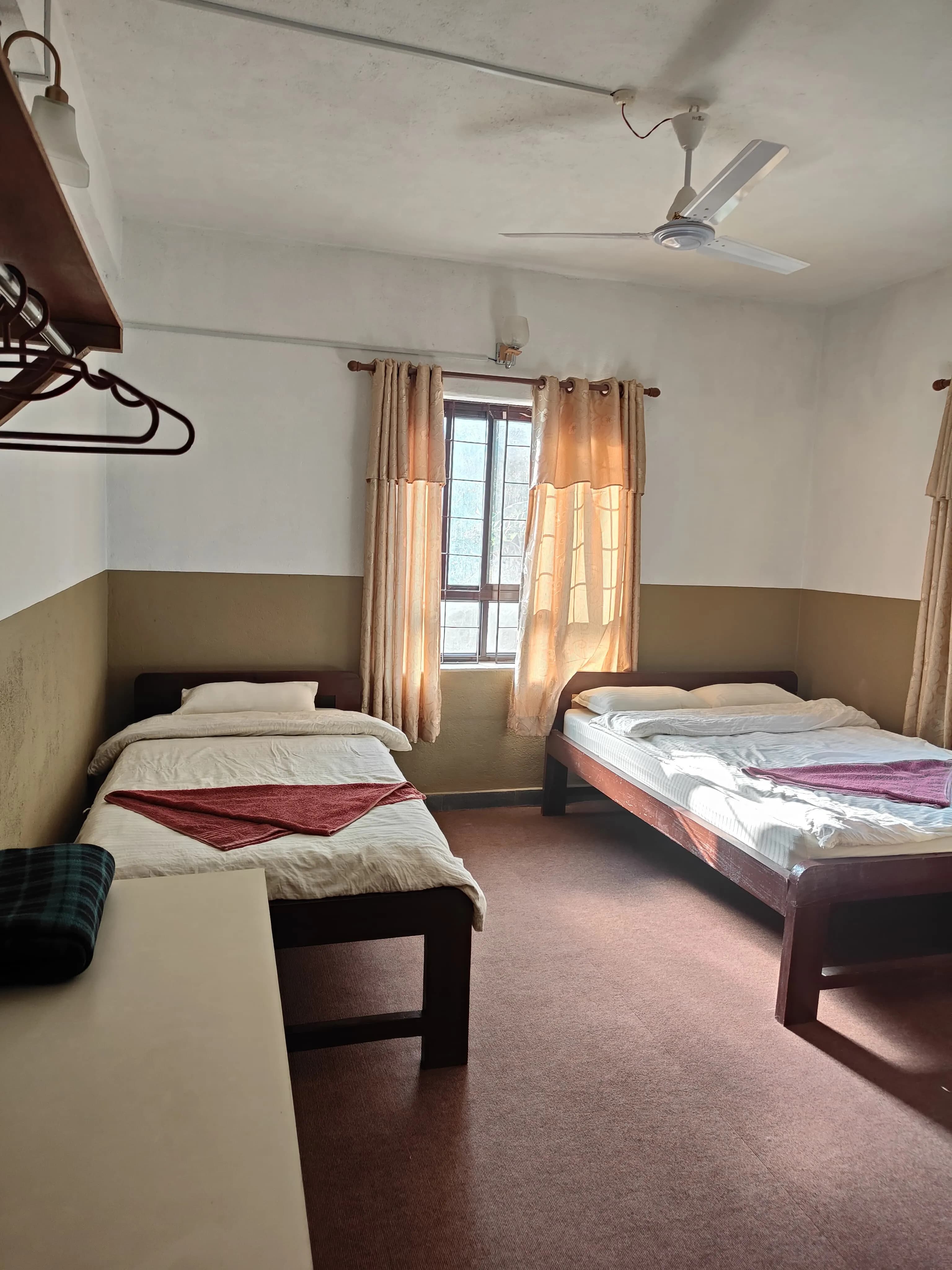 Simple wooden twin bedroom at Bodhidham ashram